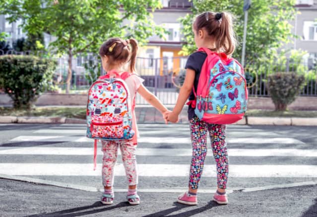 Deux petites filles qui se tiennent la main en allant à l'école pour la rentrée scolaire