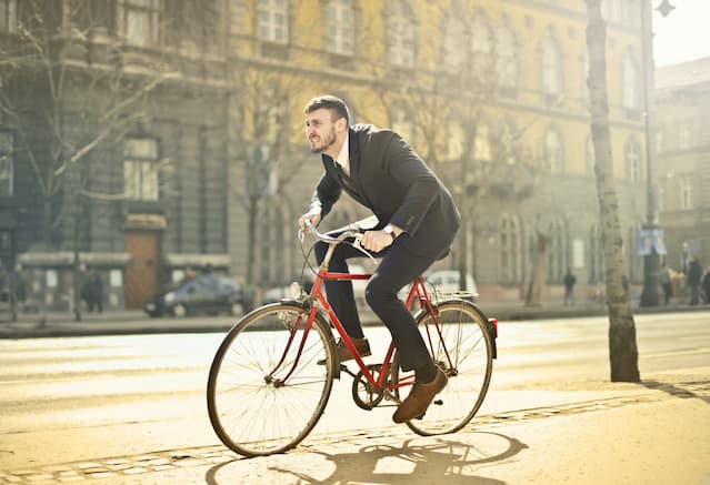 Un homme en costume gris circulant en ville sur son vélo