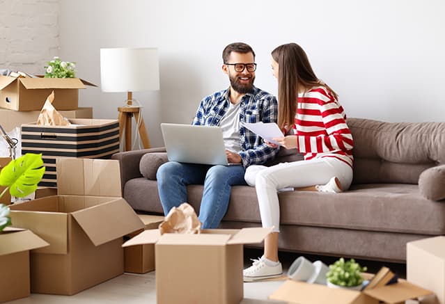 Un homme et une femme assis sur un canapé avec des cartons de déménagement