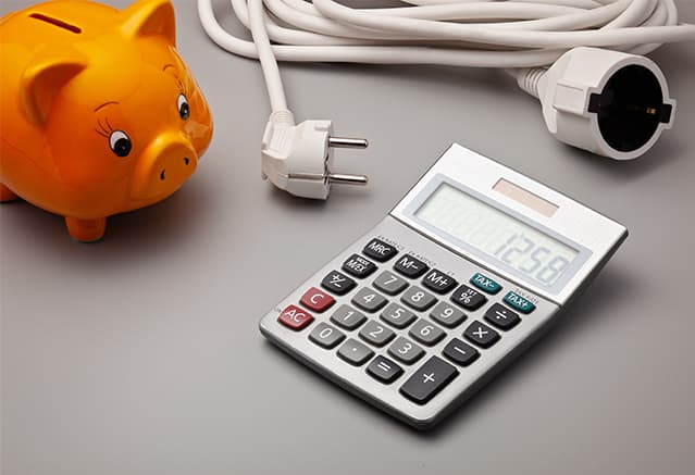 un cochon tirelire orange à côté d'une calculatrice et d'une prise électrique