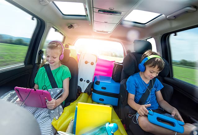 Deux enfants en voiture jouant sur leur tablette