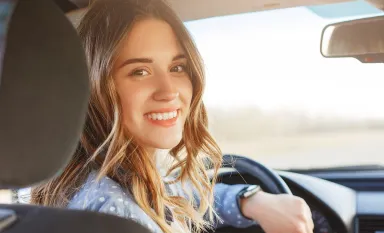 Une jeune fille souriant au volant d'une voiture