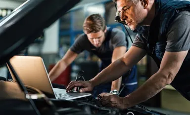 Des experts en train de contrôler sous le capot d'une voiture
