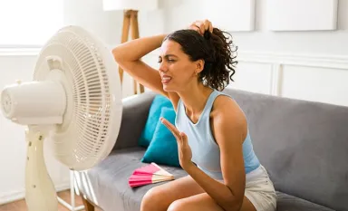 Une jeune femme devant un ventilateur pendant une vague de fortes chaleurs