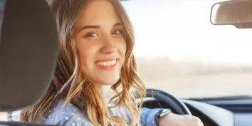 Une jeune fille souriant au volant d'une voiture