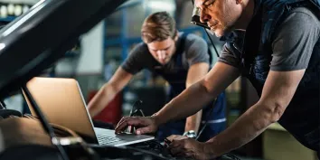 Des experts en train de contrôler sous le capot d'une voiture