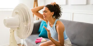 Une jeune femme devant un ventilateur pendant une vague de fortes chaleurs