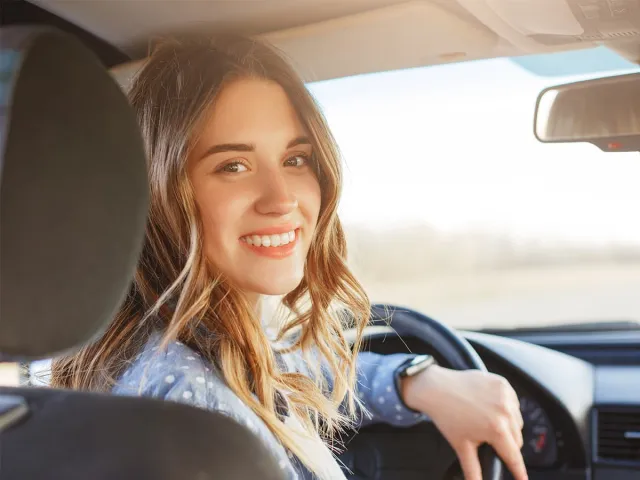 Une jeune fille souriant au volant d'une voiture