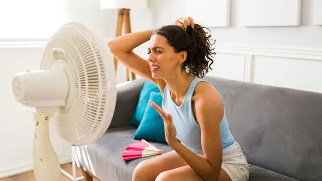 Une jeune femme devant un ventilateur pendant une vague de fortes chaleurs